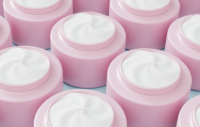 Rows of open pink skin-care jars filled with white cream, shown in close-up